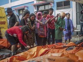 In this Sunday, Dec. 23, 2018, photo, People search for relatives among the bodies of tsunami victims in Carita, Indonesia.