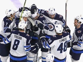Members of the Winnipeg Jets mob Mark Scheifele (center) after he scored the game-winning goal in overtime against the Chicago Blackhawks at the United Center on Friday.