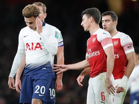 Tottenham's Dele Alli, left, reacts after a bottle was thrown at him from the stands during the English League Cup quarter final soccer match between Arsenal and Tottenham Hotspur at the Emirates stadium in London, Wednesday, Dec. 19, 2018.