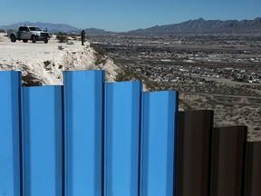 In this Jan. 25, 2017, file photo, an agent from the border patrol, observes near the Mexico-US border fence, on the Mexican side, separating the towns of Anapra, Mexico and Sunland Park, N.M.
