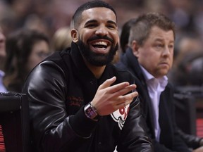 Singer and Raptors fan Drake, left, smiles as he watches his team play the Warriors during NBA action in Toronto on Thursday, Nov. 29, 2018.