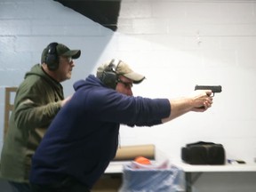 In this photo taken from a video shot on Nov. 28, 2018, Mike Carnevale places his hand on the back of Mark Hennesey while instructing him at the American Tactical Systems' indoor range in Green Island, New York.