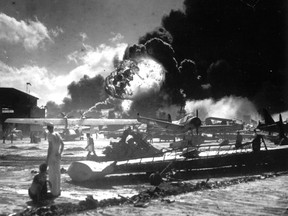 In this Dec. 7, 1941 file photo, sailors stand among wrecked airplanes at Ford Island Naval Air Station as they watch the explosion of the USS Shaw in the background, during the Japanese attack on Pearl Harbor, Hawaii.