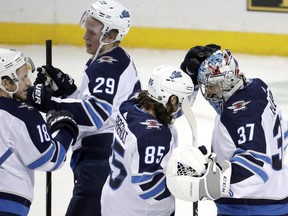 Winnipeg Jets left wing Mathieu Perreault and goaltender Connor Hellebuyck celebrate after an NHL game, Tuesday, Dec. 4, 2018, in New York.