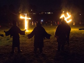 In this Saturday, April 23, 2016 photo, members of the Ku Klux Klan participate in cross and swastika burnings after a "white pride" rally in rural Paulding County near Cedar Town, Ga. (AP Photo/John Bazemore)