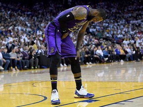 LeBron James of the Los Angeles Lakers leans over in pain after he was hurt against the Golden State Warriors during the second half of their NBA Basketball game at Oracle Arena on Dec. 25, 2018 in Oakland, Calif.