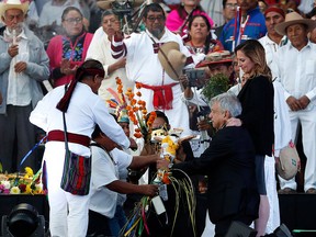 Kneeling next to his wife Beatriz Gutierrez Muller, right centre, Mexico's new President Andres Manuel Lopez Obrador is given a cross during a traditional indigenous ceremony at the Zocalo, in Mexico City, Saturday, Dec. 1, 2018.