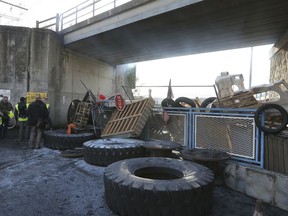 Demonstrators stand near a makeshift barricade set up by the so-called yellow jackets to block the entrance of a fuel depot in Le Mans, western France, Tuesday, Dec. 5, 2018.