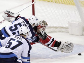 New Jersey Devils goaltender Keith Kinkaid, (right) is unable to stop a shot by Winnipeg Jets centre Mark Scheifele during overtime last night.