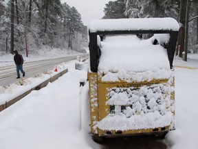 Tervante Wilkerson trudges past a snow-plastered Bobcat on Old NC 98 in Wake Forest, N.C., on Sunday, Dec. 9, 2018.