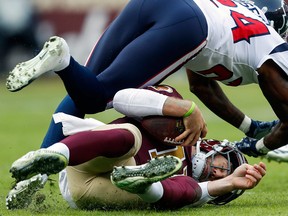 Washington Redskins quarterback Alex Smith, bottom, slides under Houston Texans cornerback Johnathan Joseph during the first half of an NFL game, Sunday, Nov. 18, 2018, in Landover, Md.