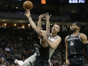 Milwaukee Bucks' Matthew Dellavedova, middle, is, fouled between Detroit Pistons' Langston Galloway and Bruce Brown during the second half of an NBA basketball game Wednesday, Dec. 5, 2018, in Milwaukee.