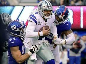 Dak Prescott #4 of the Dallas Cowboys is sacked by Olivier Vernon #54 and B.J. Hill #95 of the New York Giants during the third quarter at MetLife Stadium on December 30, 2018 in East Rutherford, New Jersey.