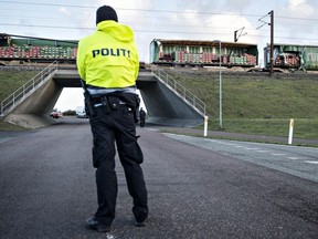 A policeman blocks the road as in background can be seen a cargo train with damaged containers after access to the Great Belt Bridge was closed following a railway accident on January 2, 2019 in Nyborg, Denmark. - Six people were killed in a train accident on a bridge connecting two islands in Denmark, rail operator DSB said. The accident occurred on the Great Belt Bridge connecting the islands of Zealand, where Copenhagen is located, and Funen.