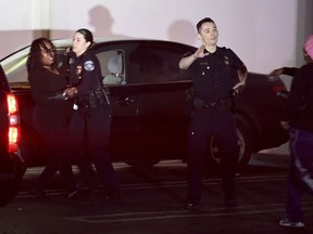 A woman has to be restrained by a police officer at the scene of a shooting at the Gable House Bowl in Torrance, Calif., on Saturday, Jan. 5, 2019.