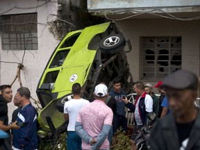 People stand around a car that was overturned by a tornado in Havana, Cuba, Monday, Jan. 28, 2019. A tornado and pounding rains smashed into the eastern part of Cuba's capital overnight, toppling trees, bending power poles and flinging shards of metal roofing through the air as the storm cut a path of destruction across eastern Habana.
