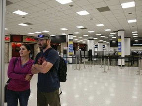 Confused travelers look to find their concourse as they walk past a closed down terminal at the Miami International Airport on Saturday, Jan. 12, 2019, in Miami. The partial government shutdown is starting to strain the national aviation system, with unpaid security screeners staying home, air-traffic controllers suing the government and safety inspectors off the job.