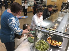 U.S. Coast Guard spouse Mariah Battermann, left, fills her plate, Tuesday, Jan. 15, 2019, at Roger Williams University in Bristol, R.I.