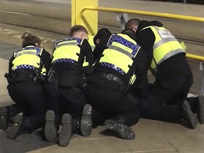 Police restrain a man after he stabbed three people at Victoria Station in Manchester, England, late Monday Dec. 31, 2018. (Sam Clack/PA via AP)