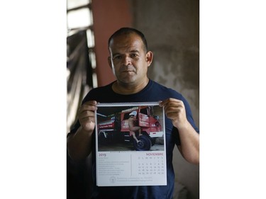 In this Jan. 12, 2019 photo, firefighter Commander Alcides Britez holds a calendar page with a photo of himself posing nude, in Asuncion, Paraguay.