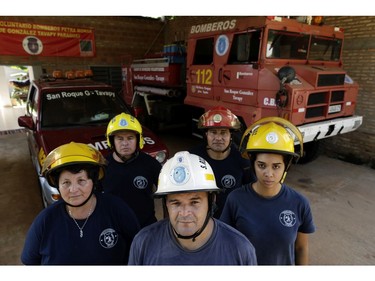 In this Jan. 13, 2019 photo, Commander Alcides Britez, center, and a group of firefighters pose for a photo at their fire station in San Roque Gonzalez, Paraguay.