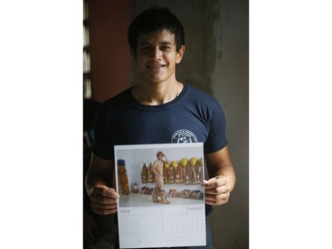In this Jan. 12, 2019 photo, firefighter Daniel Rodriguez poses holding a calendar page with a nude photo of himself, in Asuncion, Paraguay.
