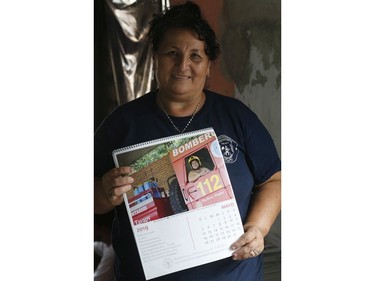 In this Jan. 12, 2019 photo, firefighter Natividad Ayala García holds a calendar page with a photo of herself posing nude inside a fire truck, in Asuncion, Paraguay.