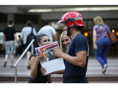 In this Jan. 13, 2019 photo, firefighter Daniel Rodriguez sells calendars to a couple of women in Asuncion, Paraguay.