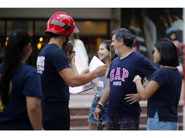 In this Jan. 13, 2019 photo, firefighter Daniel Rodriguez sells calendars to a family, in Asuncion, Paraguay.