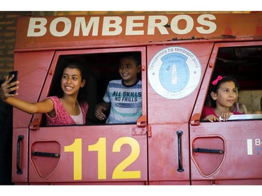 In this Jan. 13, 2019 photo, sons and daughters of firefighters take selfies inside the fire truck during a visit to the station in San Roque Gonzalez, Paraguay. Other members of the department also juggle firefighting with jobs as teachers, journalists or plumbers, while some still attend nursing school or are finishing a law degree.