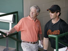 This March 1, 2008, file photo shows San Francisco Giants managing general partner Peter Magowan, left, visiting with centre fielder Aaron Rowand, right, in the dugout prior to their spring training baseball game against the Oakland Athletics in Scottsdale, Ariz.