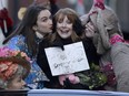 Actor Bryce Dallas Howard, center, Hasty Pudding Woman of the Year, is kissed by Harvard University theatrical students Grace Ramsey, left, and David Lynch, right, as they ride in the back of a convertible during a parade, Thursday, Jan. 31, 2019 through Harvard Square, in Cambridge, Mass.
