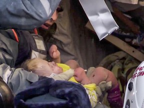 This photo provided by the Russian Emergency Situations Ministry taken from TV footage shows Emergency Situations employees save a 10-month-old baby at the scene of a collapsed section of an apartment building, in Magnitigorsk, a city of 400,000 about 1,400 kilometres (870 miles) southeast of Moscow, Russia, Tuesday, Jan. 1, 2019. (Russian Ministry for Emergency Situations photo via AP)