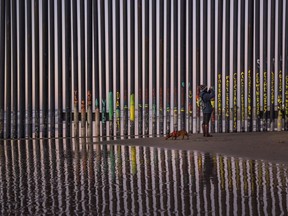 A woman takes a photo by the border fence between San Diego, Calif., and Tijuana, as seen from Mexico, on Jan. 3, 2019.