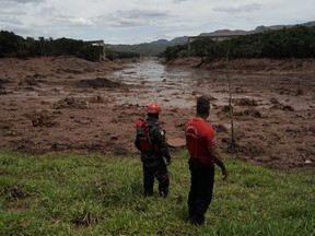 Civil firefighters survey a destroyed rail bridge two days after a dam collapse in Brumadinho, Brazil, Sunday, Jan. 27, 2019. Brazilian officials on Sunday suspended the search for potential survivors of a dam collapse that has killed at least 40 people amid fears that another nearby dam owned by the same company was also at risk of breaching.