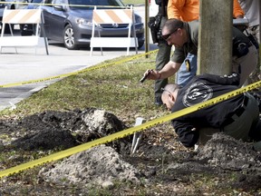 FBI and Pembroke Pines Police investigate a tunnel by a possible would-be bank robber which was discovered beneath the entrance to the Flamingo Pines shopping plaza Wednesday, Jan. 30, 2019, in Pembroke Pines, Fla. (Taimy Alvarez/South Florida Sun-Sentinel via AP)