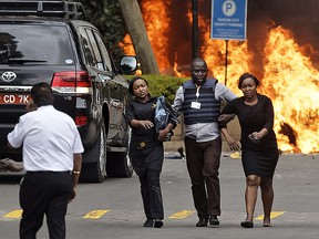 Security forces help civilians flee the scene as cars burn behind, at a hotel complex in Nairobi, Kenya Tuesday, Jan. 15, 2019. (AP Photo/Ben Curtis)