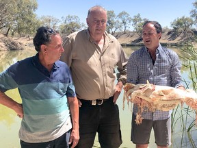 This screen grab taken from video taken on January 10, 2019 released by the office of New South Wales MP Jeremy Buckingham shows him holding a Murray cod, which was killed during a massive fish kill in Menindee on the Darling River, as local residents Dick Arnold (left) and Rob McBride from Tolarno Station look on. (Getty Images)