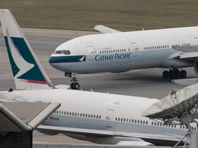 In this file photo taken on March 15, 2017 a Cathay Pacific Boeing 777 passenger aircraft (top) taxis past a stationary plane on the tarmac at the international airport in Hong Kong. (ANTHONY WALLACE/AFP/Getty Images)