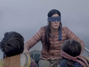 Sandra Bullock plays a woman trying to guide two small children (Julian Edwards, left, and Vivien Lyra Blair, right) to safety in the post-apocalyptic thriller "Bird Box." (Netflix)