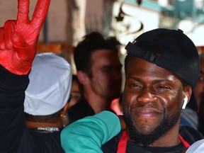 Actor Kevin Hart gestures between serving volunteers who will serve the homeless at the annual L.A. Mission Thanksgiving meal for the homeless on Skid Row in Los Angeles, Calif. on Nov. 21, 2018, where some 3,500 meals will be served. (FREDERIC J. BROWN/AFP/Getty Images)
