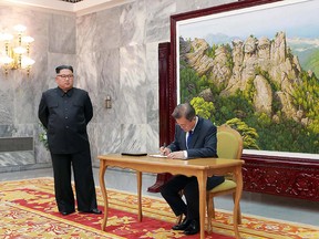This photograph taken on May 26, 2018 and released by North Korea's official Korean Central News Agency (KCNA) on May 27 shows South Korea's President Moon Jae-in signing a guestbook as North Korea's leader Kim Jong Un looks on. (Getty Images)