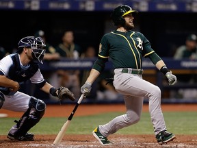 In this Sept. 15, 2018, file photo, Oakland Athletics' Jed Lowrie, right, lines an RBI-single off Tampa Bay Rays pitcher Yonny Chirinos as Rays catcher Nick Ciuffo, left, looks on during the third inning of a baseball game in St. Petersburg, Fla.