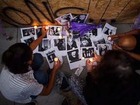 Friends of 18-year-old Danforth shooting victim Reese Fallon, leave candles on pictures of their friend Reese at a makeshift memorial remembering the victims of a shooting on Sunday evening on Danforth Ave. in Toronto on Monday, July 23, 2018.