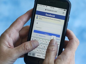 In this Aug. 21, 2018 file photo, a Facebook page is shown on a smartphone in Surfside, Fla. (AP Photo/Wilfredo Lee, File)