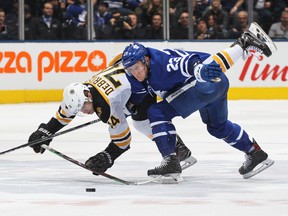 Jake DeBrusk of the Boston Bruins (left) battles against Travis Dermott of the Maple Leafs on Saturday night at Scotiabank Arena. (GETTY IMAGES)