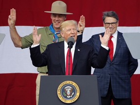 In this July 24, 2017 file photo, President Donald Trump, front left, gestures as former boys scouts, Interior Secretary Ryan Zinke, left, and Energy Secretary Rick Perry, watch at the 2017 National Boy Scout Jamboree at the Summit in Glen Jean, W.Va. (AP Photo/Steve Helber, File)