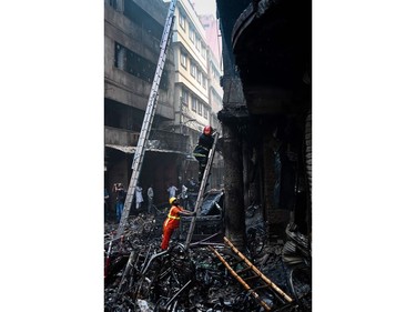 A firefighter climbs a ladder for an inspection in the aftermath of a fire that broke out in Dhaka on Feb. 21, 2019.