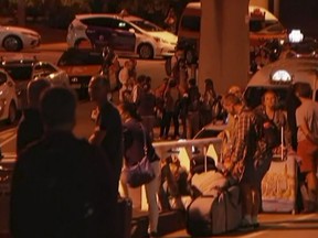 In this image made from a video taken on Saturday, Feb. 2, 2019, travelers stay outside Brisbane International Airport after their evacuation from the airport in Brisbane, Australia. (Australian Broadcasting Corporation via AP)