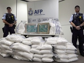 Police guard some of the 1.4 tons of seized ephedrine that is piled up during an Australian Federal Police press conference in Melbourne, Wednesday, Feb. 27, 2019. Australian authorities say they seized chemicals which could have been used to make one ton of methamphetamine and arrested four men in a joint operation with China.